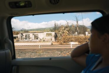 person in car looking outside, driving by maui