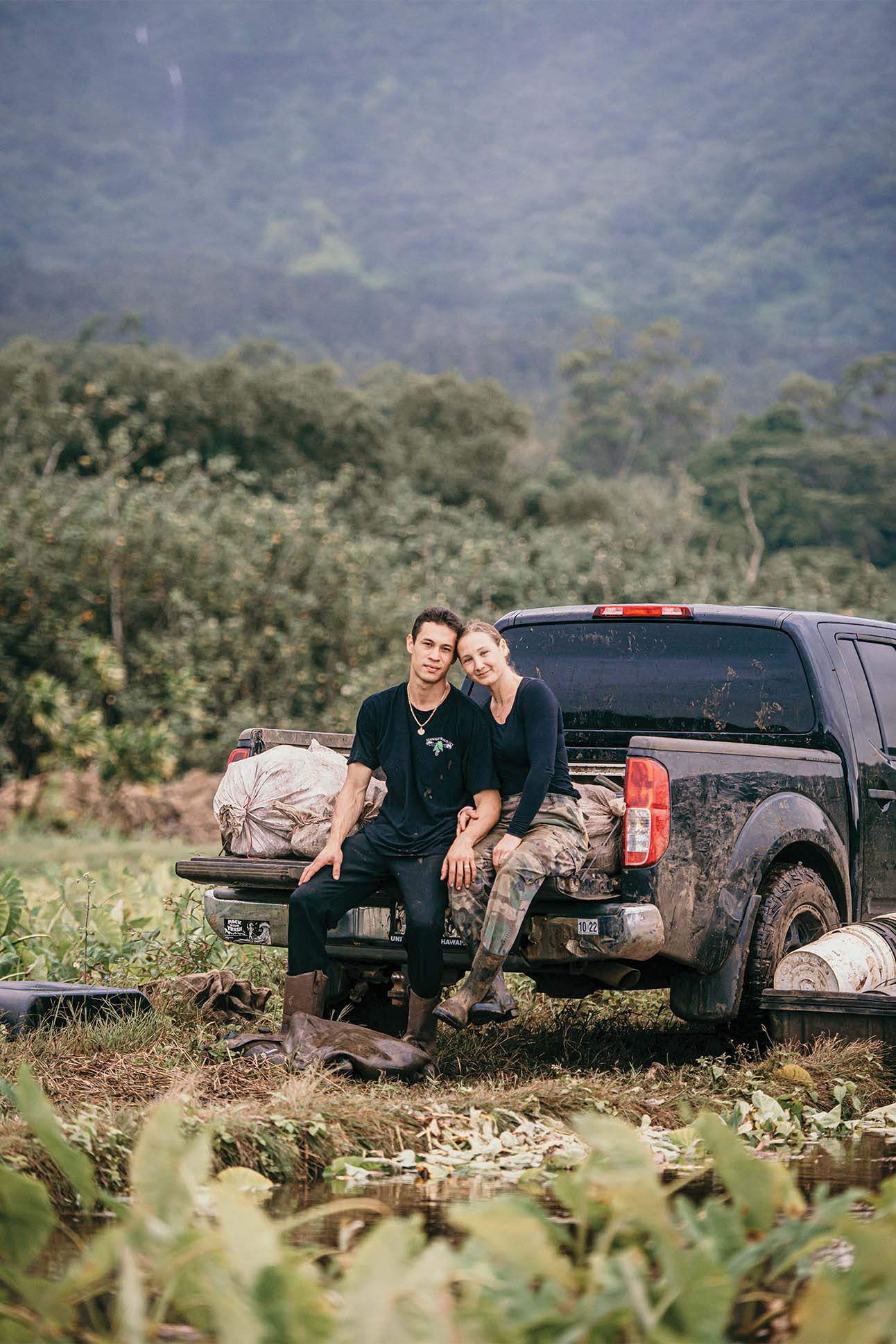 a couple sitting at the back of a truck on a farm in Hanalei